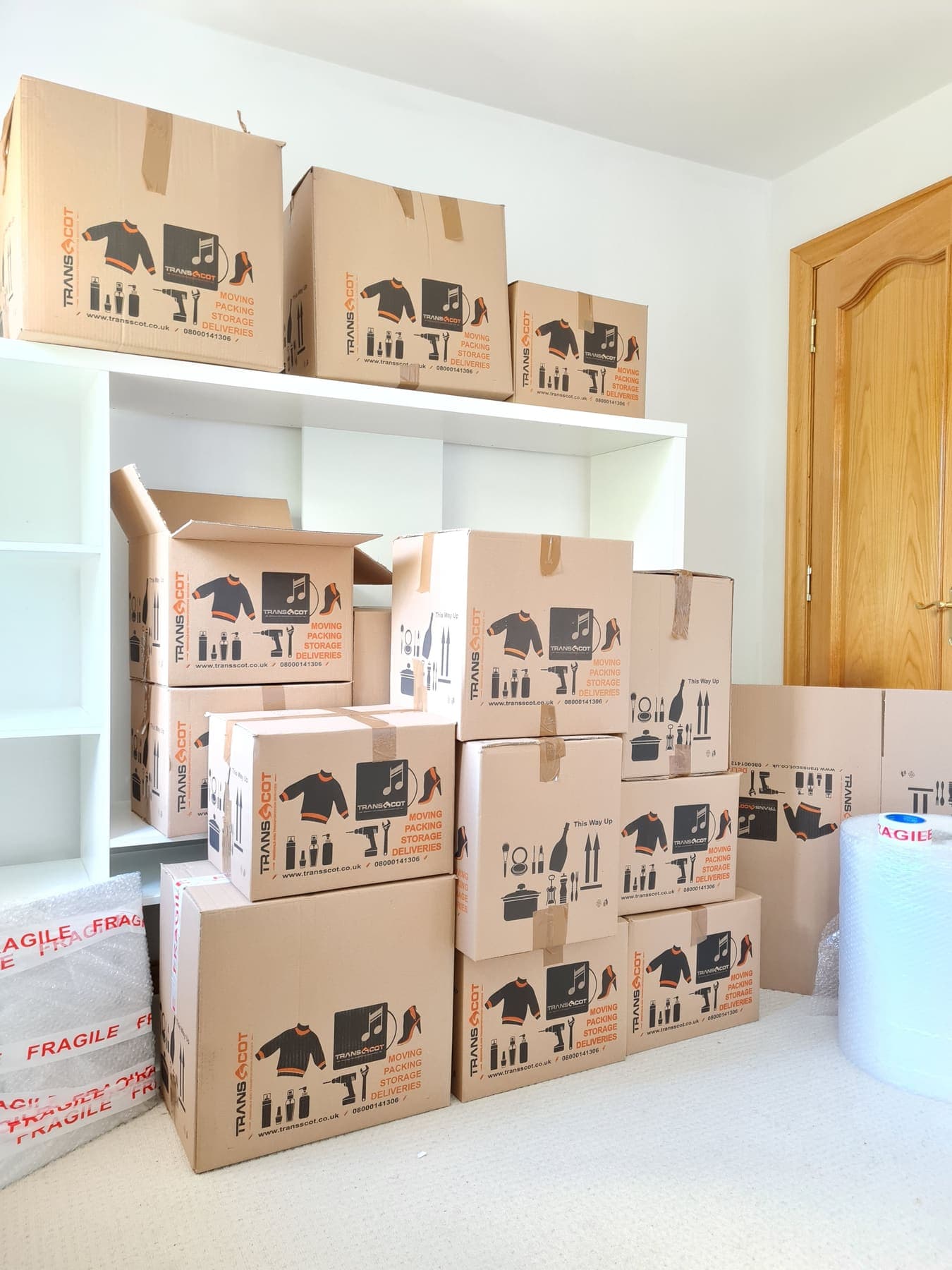 A room packed and stacked with TransScot branded moving boxes, ready for collection